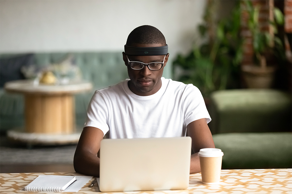 Man on computer wearing Neurovine Sensorband
