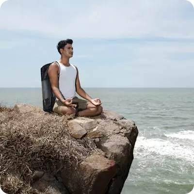 Man sitting on a rock overlooking the ocean